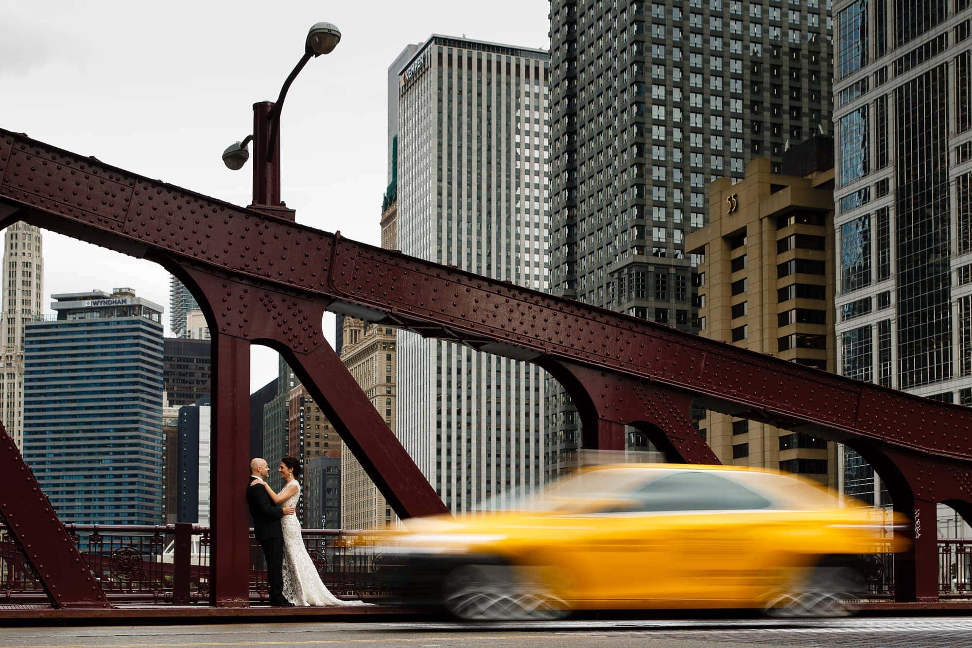 Christina and Brad share a moment together on their wedding day near the State Street bridge as a taxi drives by
