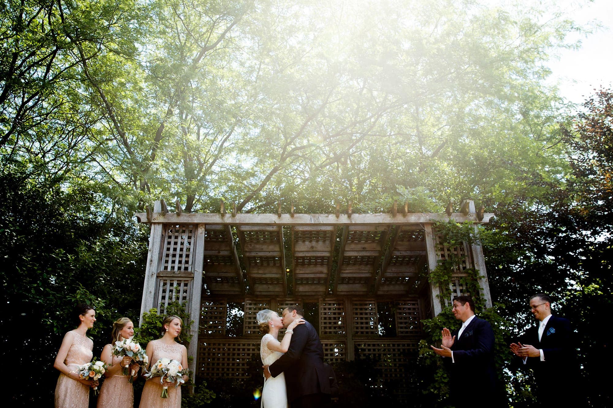 A groom kisses hits bride for the first time under the arbor outside during their morning wedding at Galleria Marchetti in Chicago, Illinois.