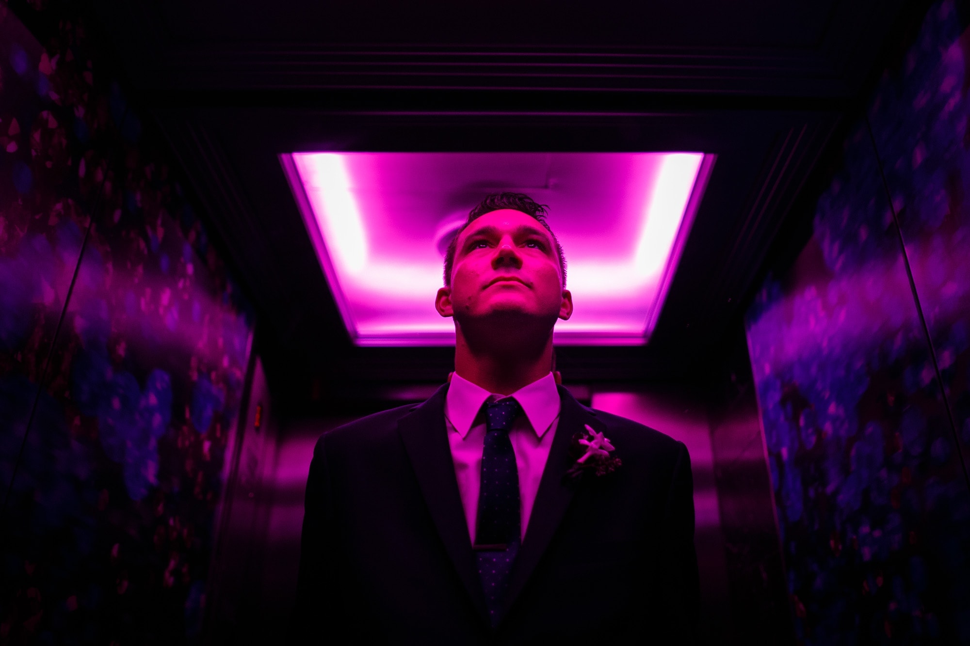 A groom waits in a colorful elevator on the way to his wedding in Chicago
