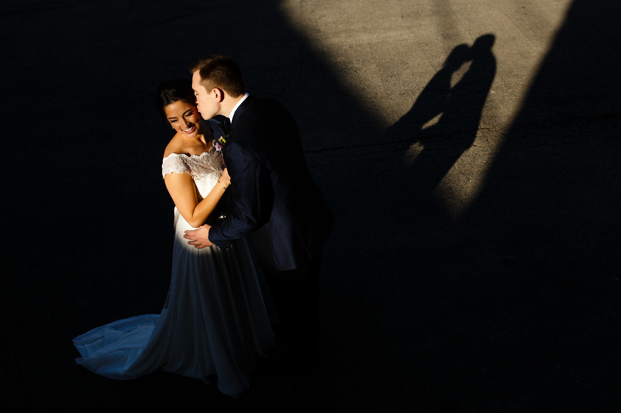 A shaft of light illuminates Bryce and Johnna during a kiss on the cheek outside of Loft on Lake in Chicago.