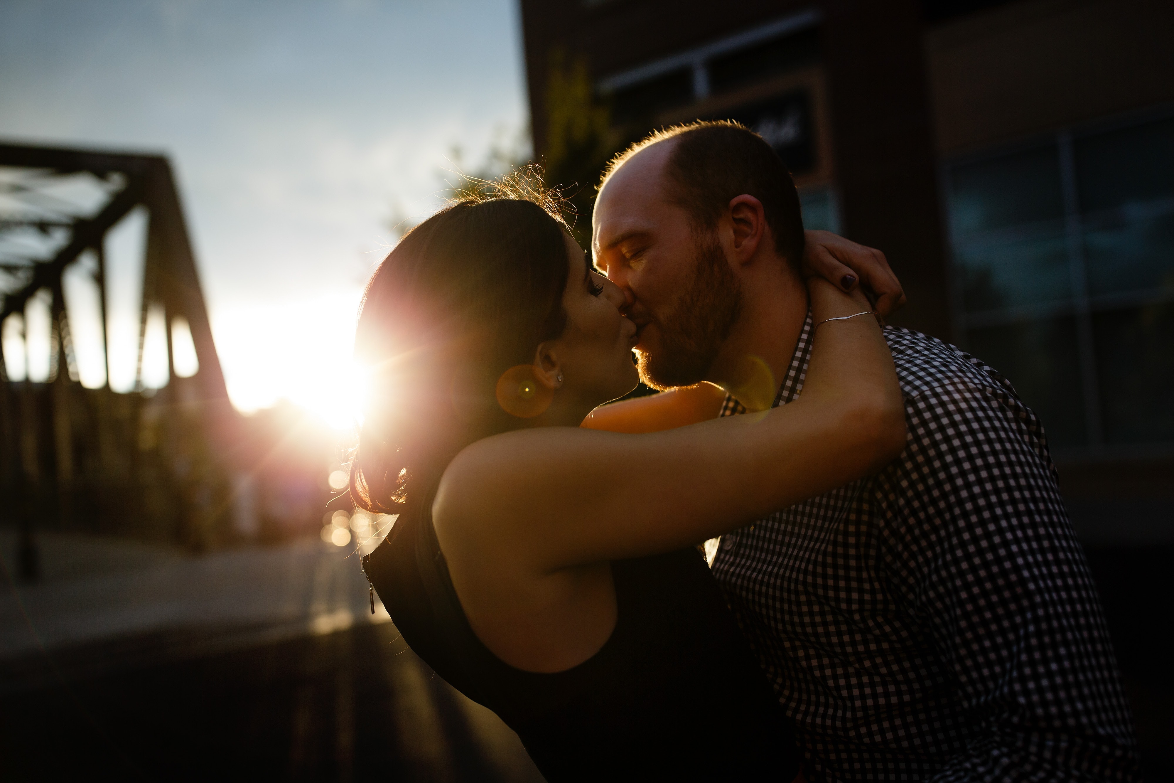 The sunlight flares past the Wynkoop Street bridge as Chris and Angie kiss