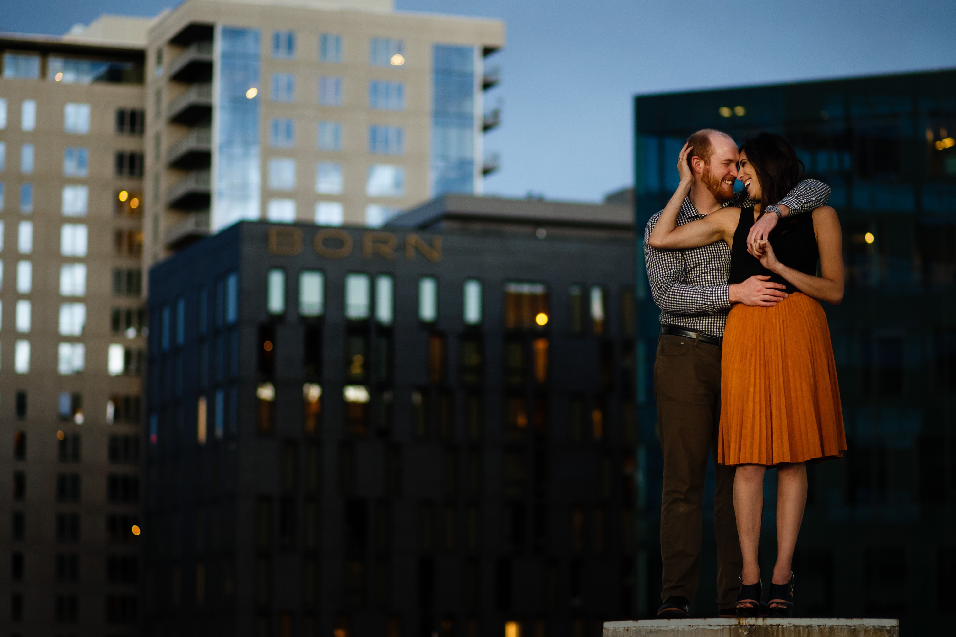Angie and Chris pose on top of a parking garage in the LoDo neighborhood of Denver during their engagement photos