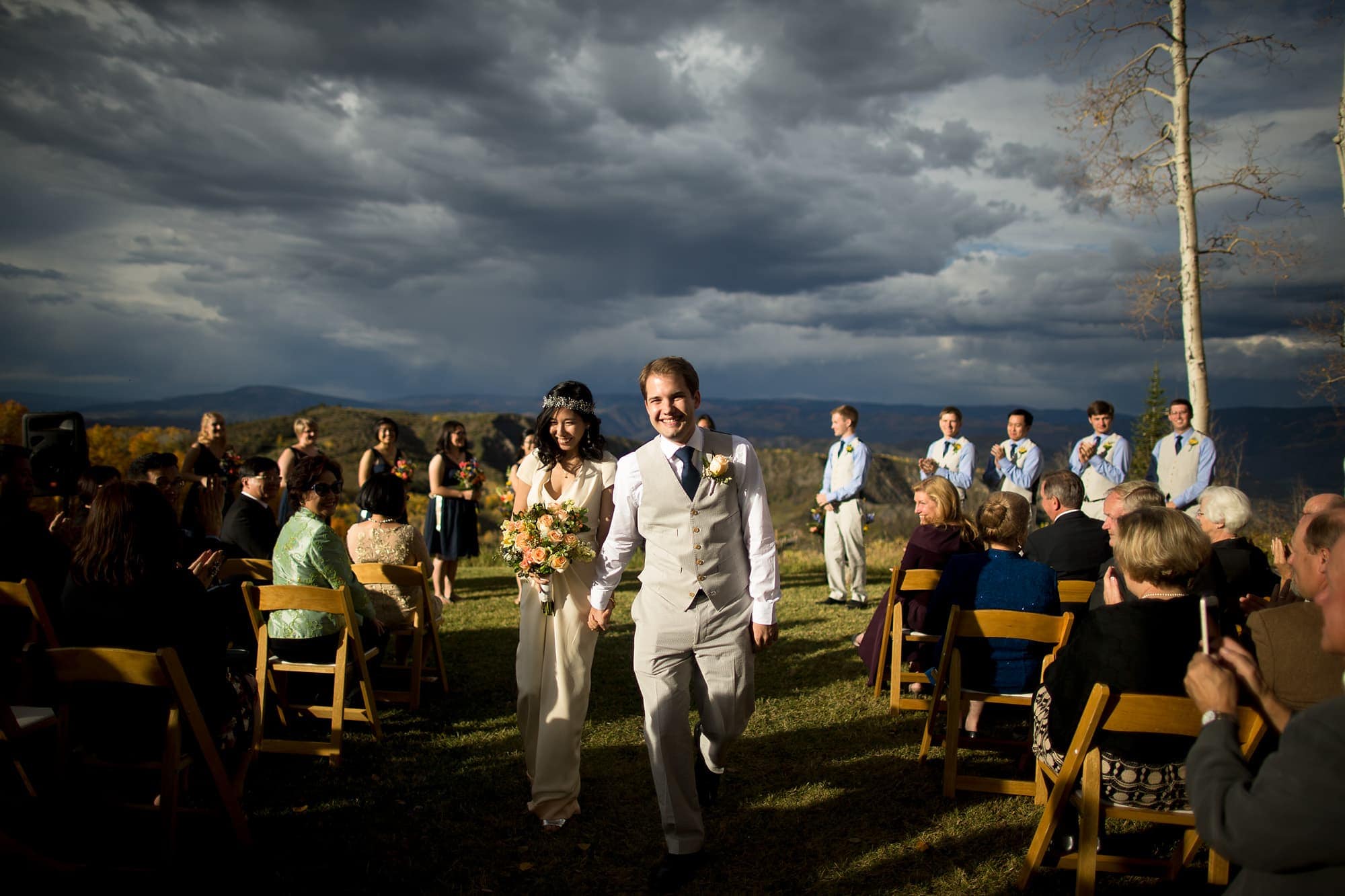 The newly married couple walk back down the aisle after their Lynn Britt Cabin wedding ceremony in Snowmass Village near Aspen, Colorado.