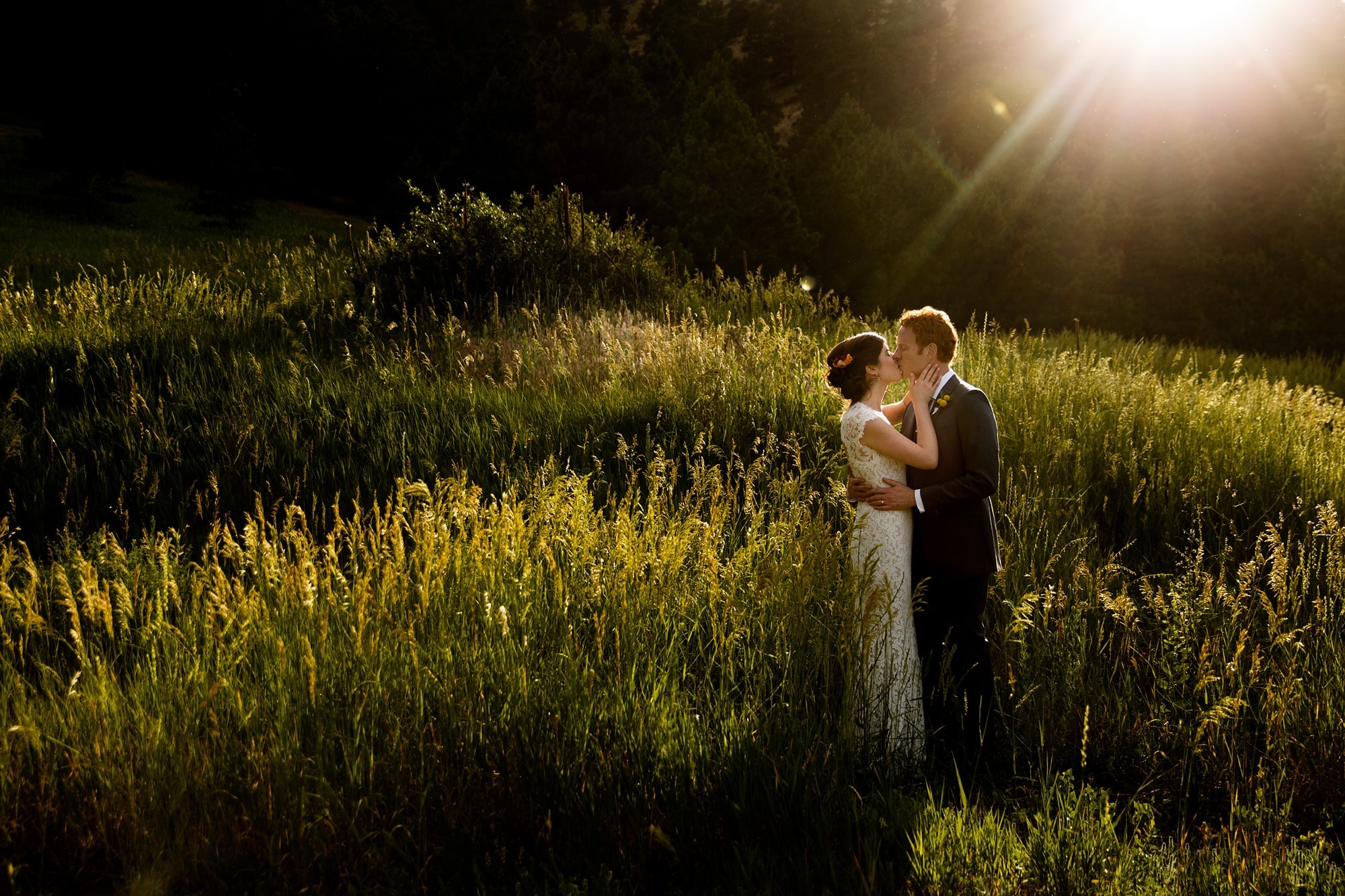 The sun flares over the couple as they kiss in Boulder near Centennial trailhead