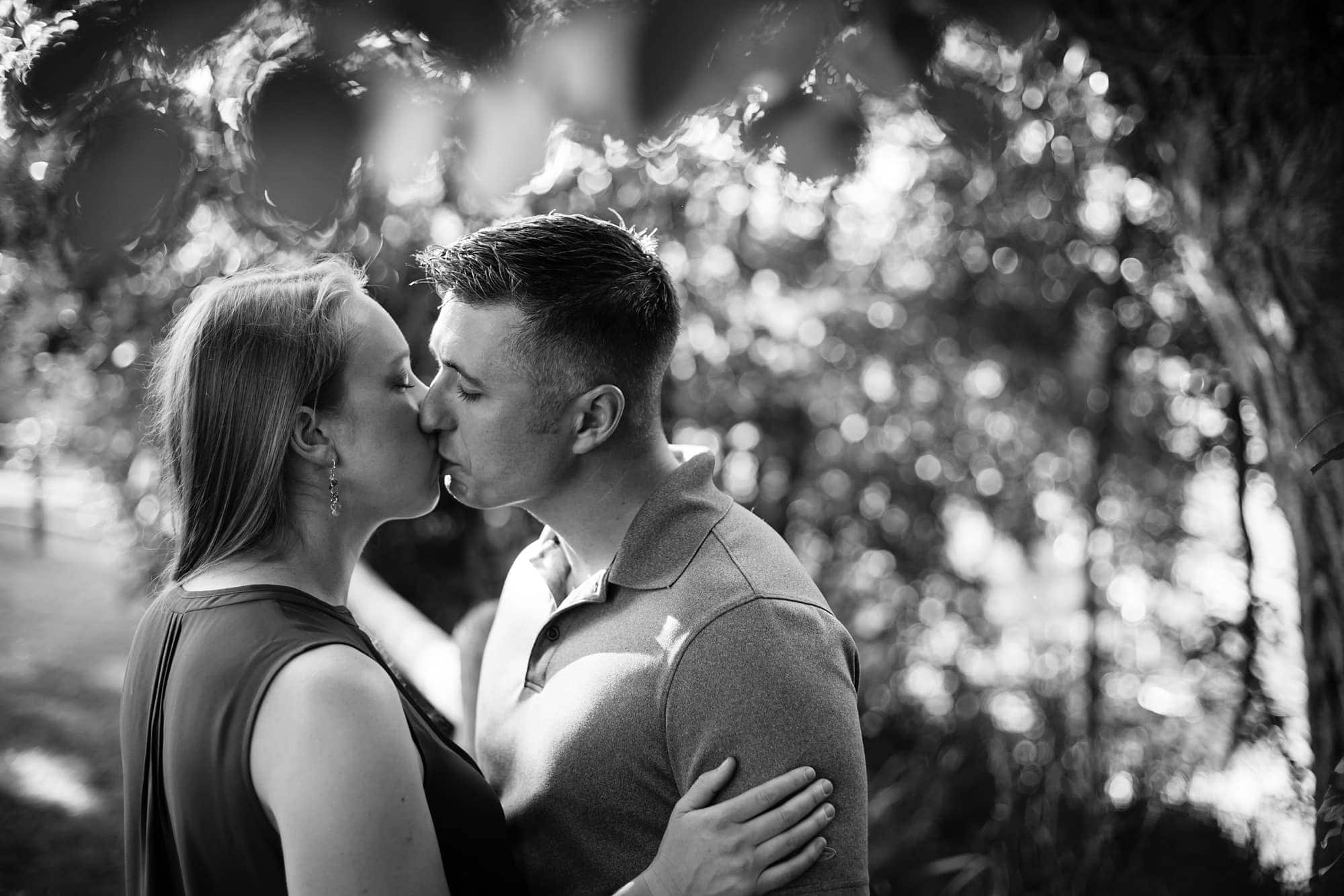 A couple share a kiss under a tree in Littleton