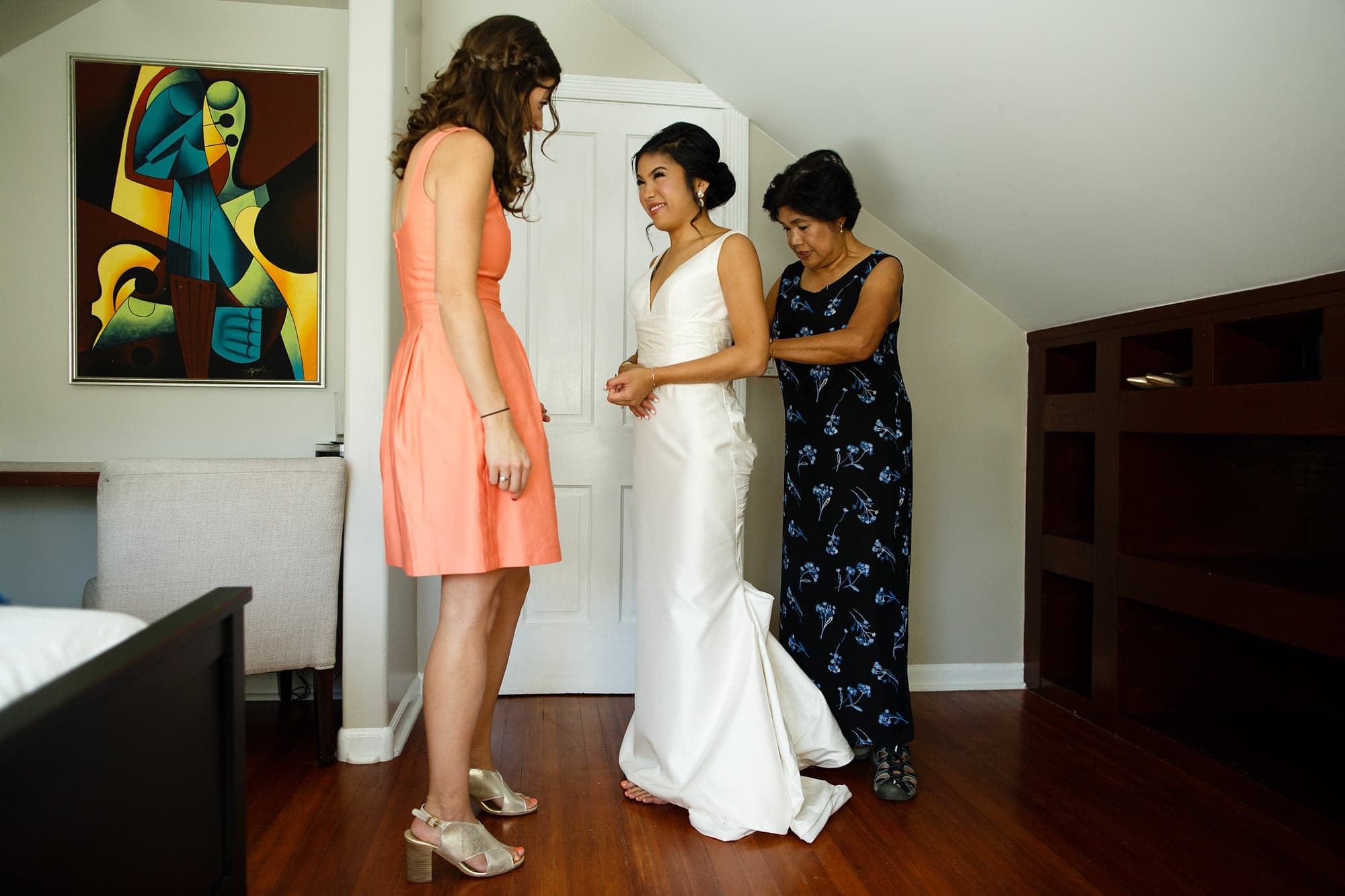 The bride gets into her wedding dress with help from her mother and maid of honor at an Air BnB home in Boulder, Colorado