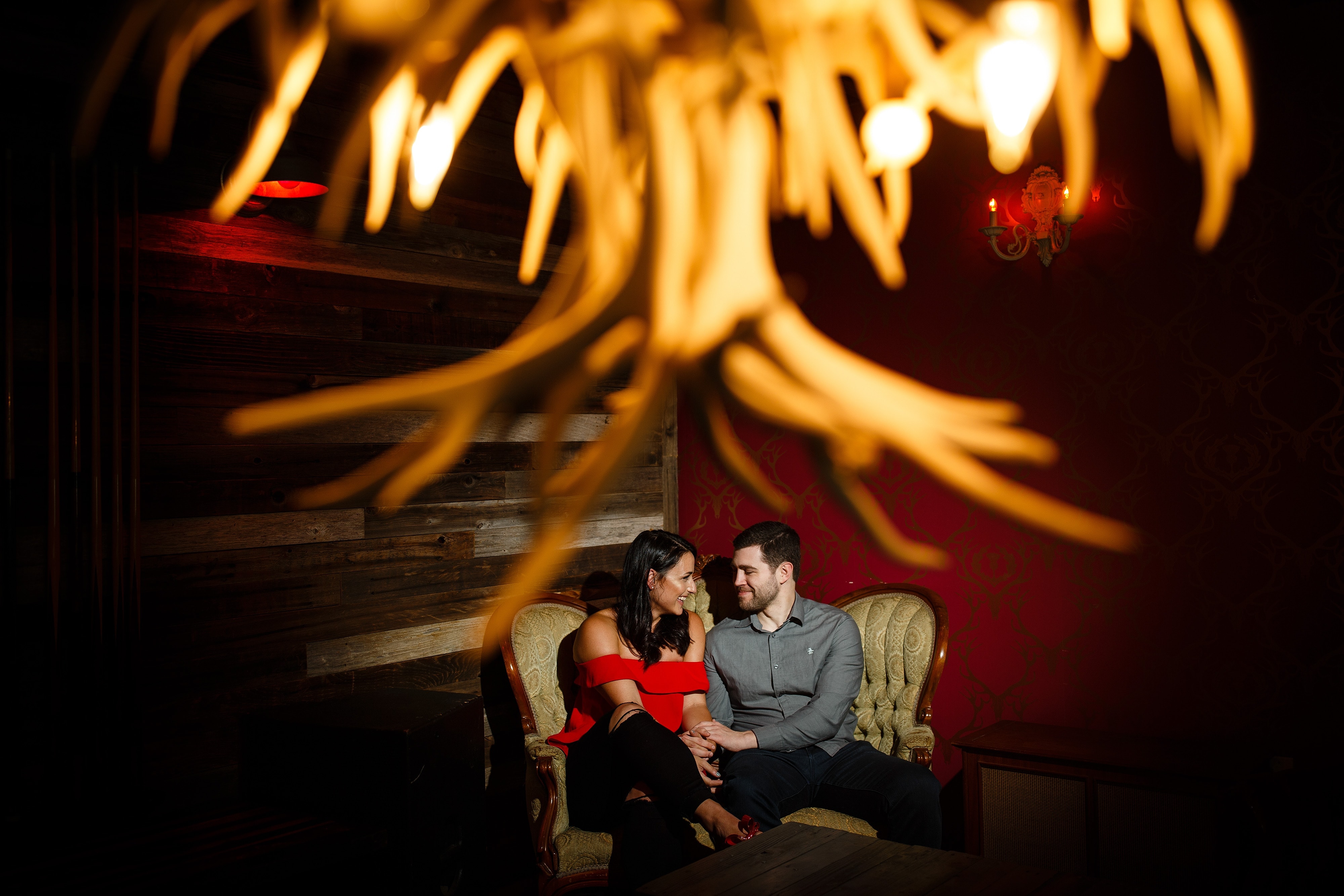 Danielle cuddles on the couch with Jordan while having a drink at The Curtis Club during their engagement session in Denver