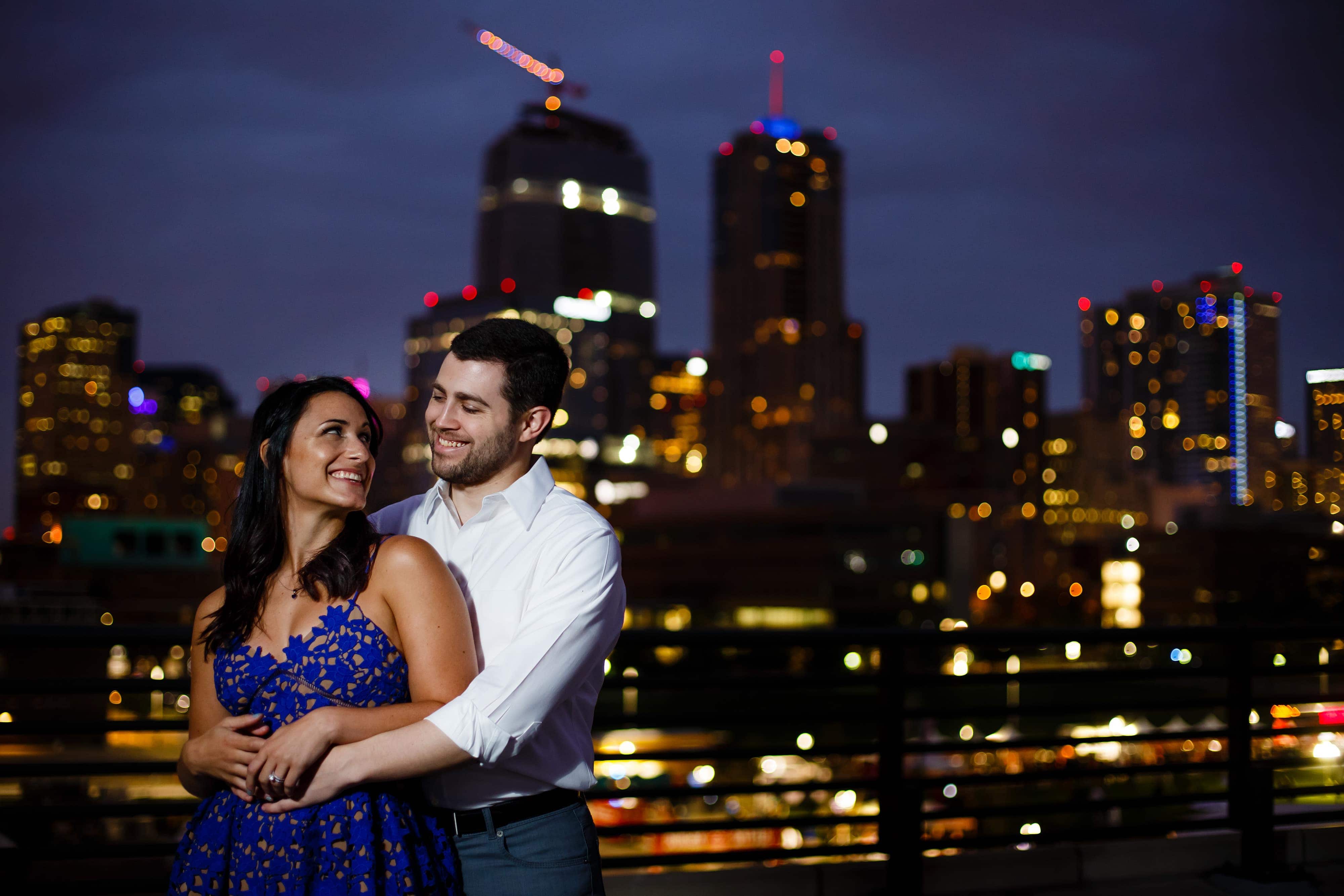 Danielle and Jordan pose together with the Denver skyline in the background during their engagement photos near LoDo
