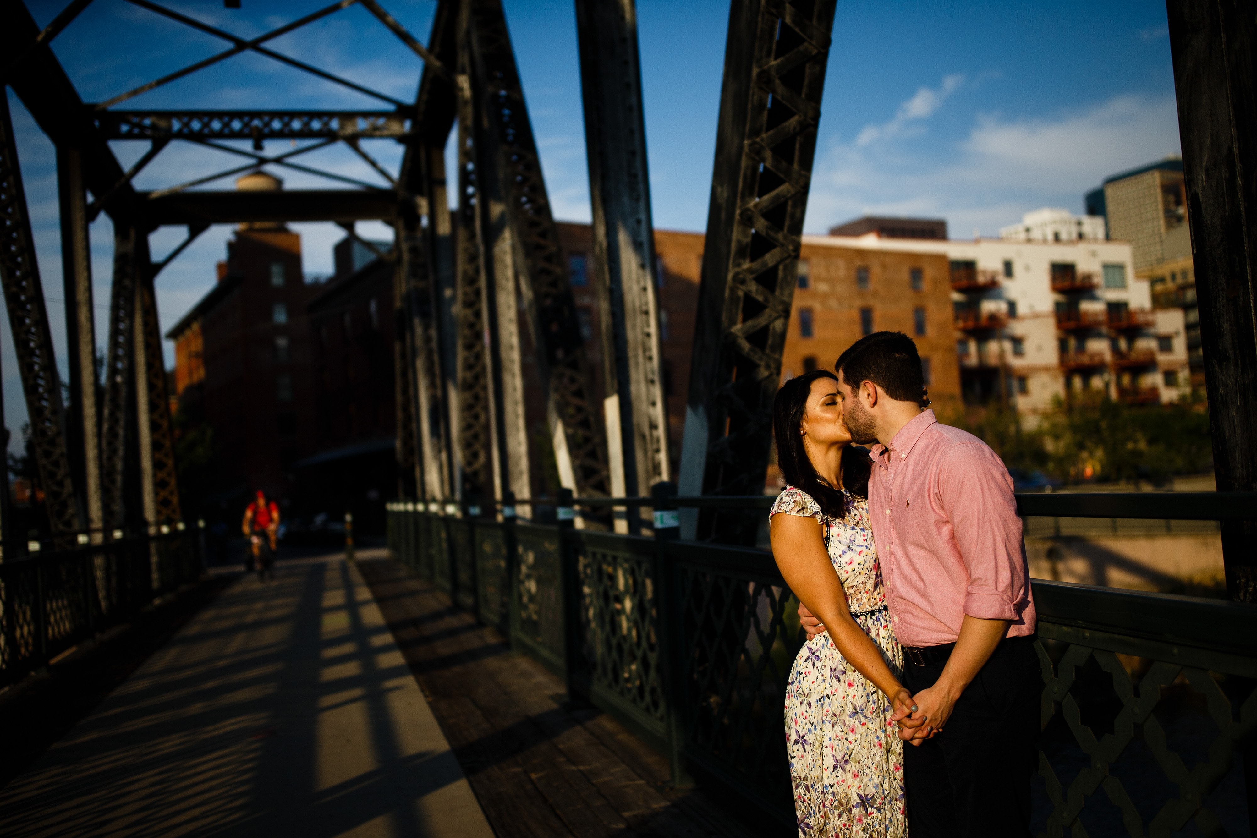 Jordan and Danielle kiss on the Wynkoop bridge during their downtown Denver engagement session in the LoDo neighborhood in August