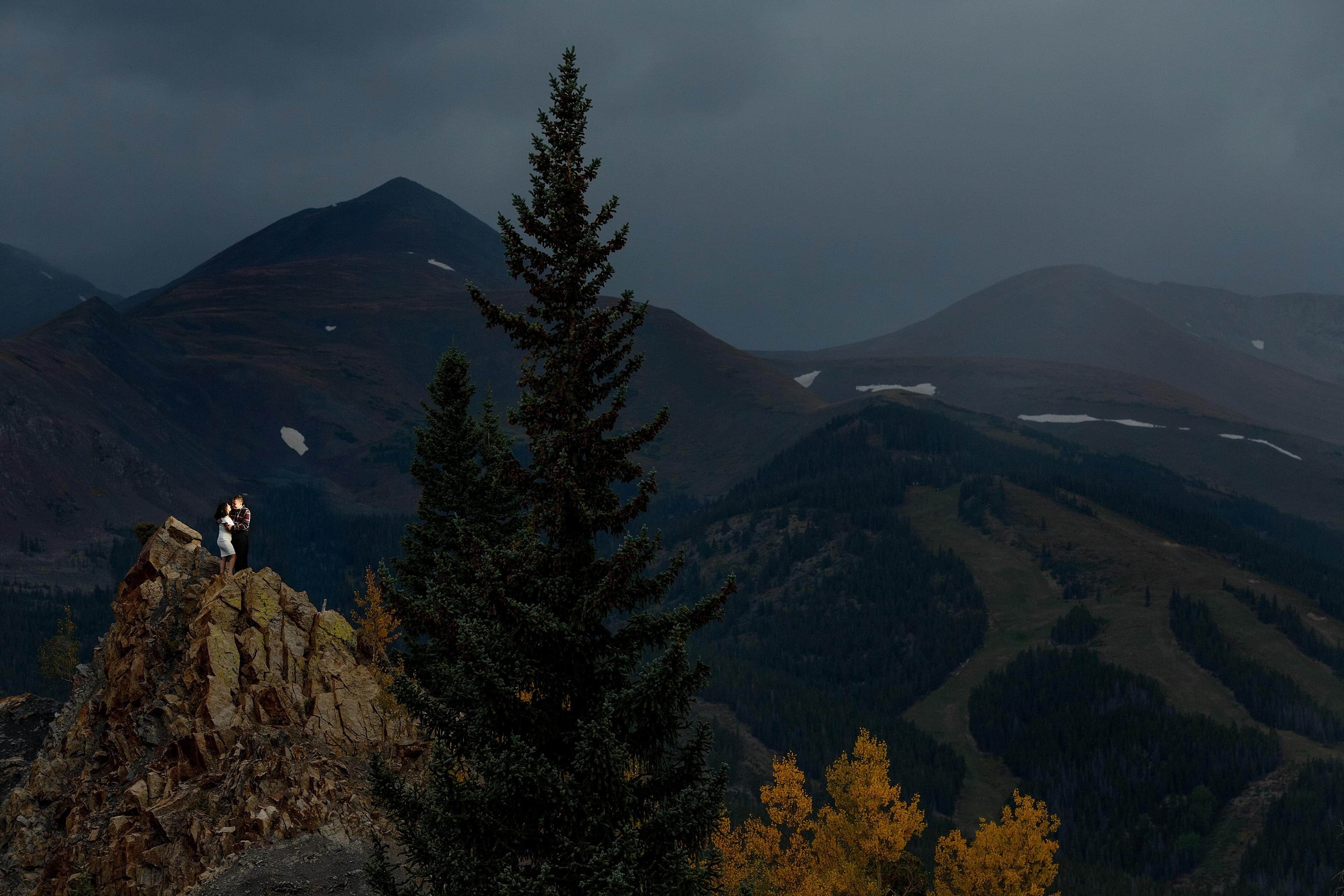 Joseph and Shabnam embrace during their Breckenridge fall colors engagement photos on a rock face along Boreas Pass road