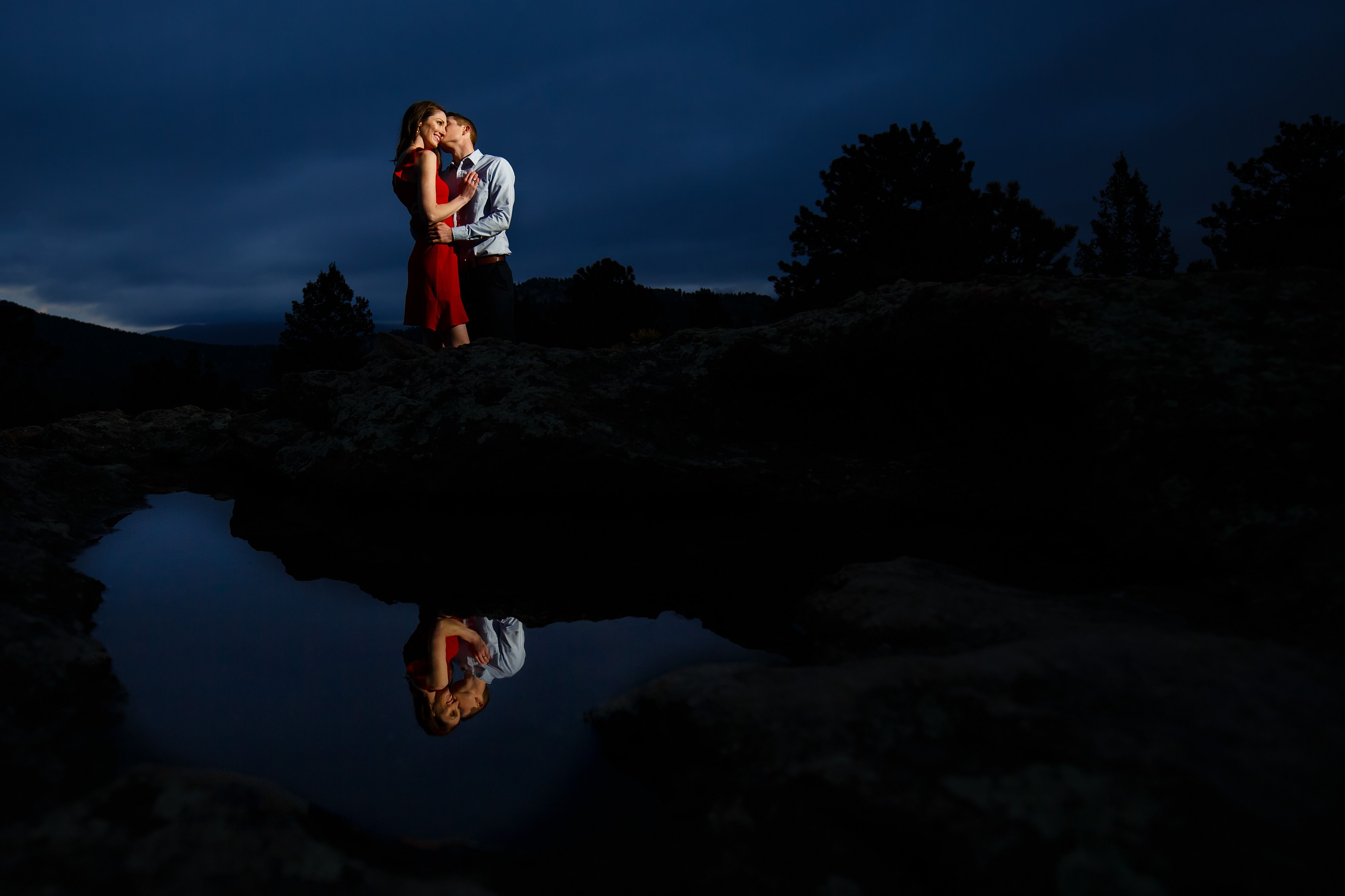 A couple is reflected in a pool of water while posing at Brother's Lookout in Alderfer Three Sister's Park during their Evergreen engagement photos