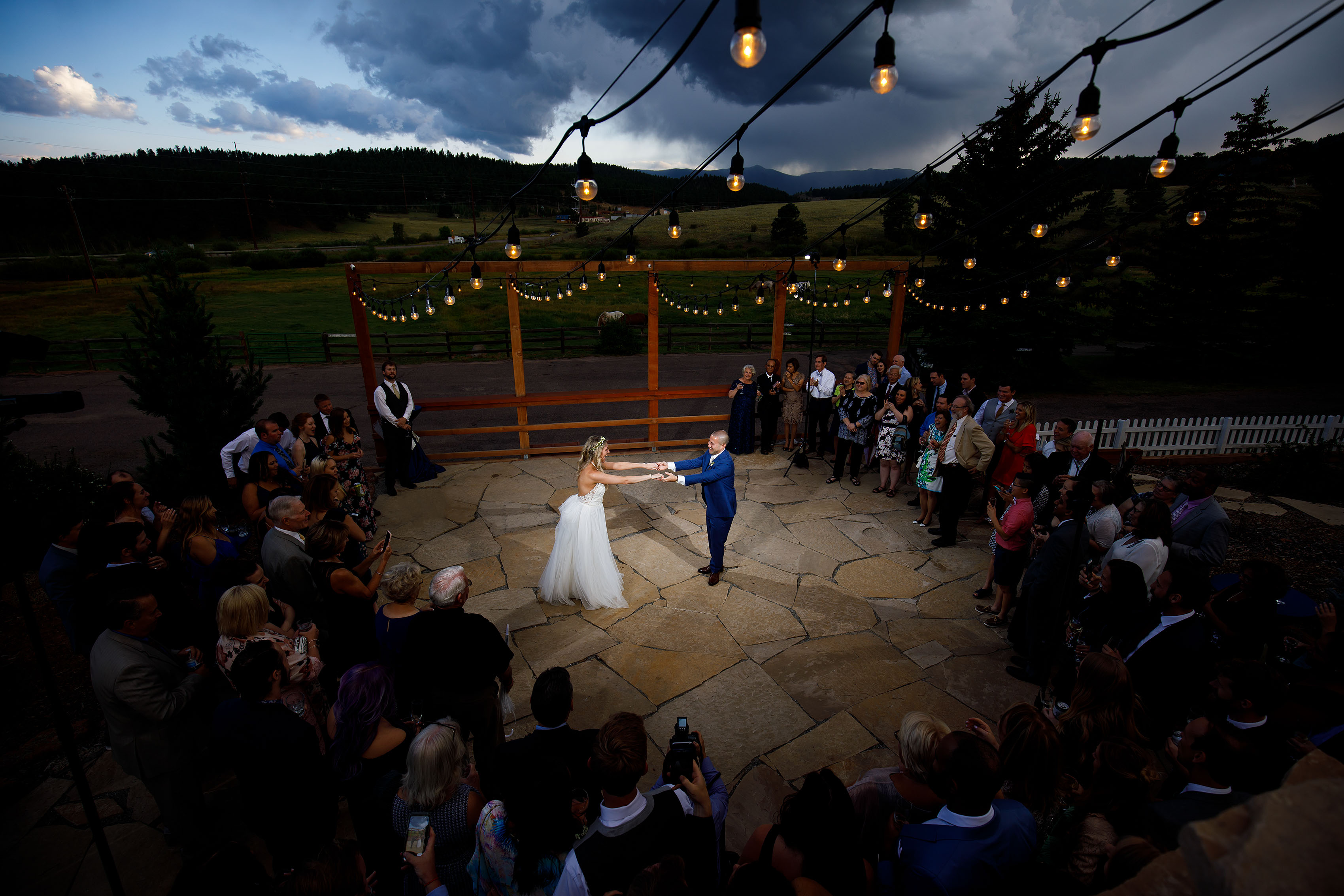 The newlyweds dance on the patio under market lights during their summer barn wedding at Deer Creek Valley Ranch