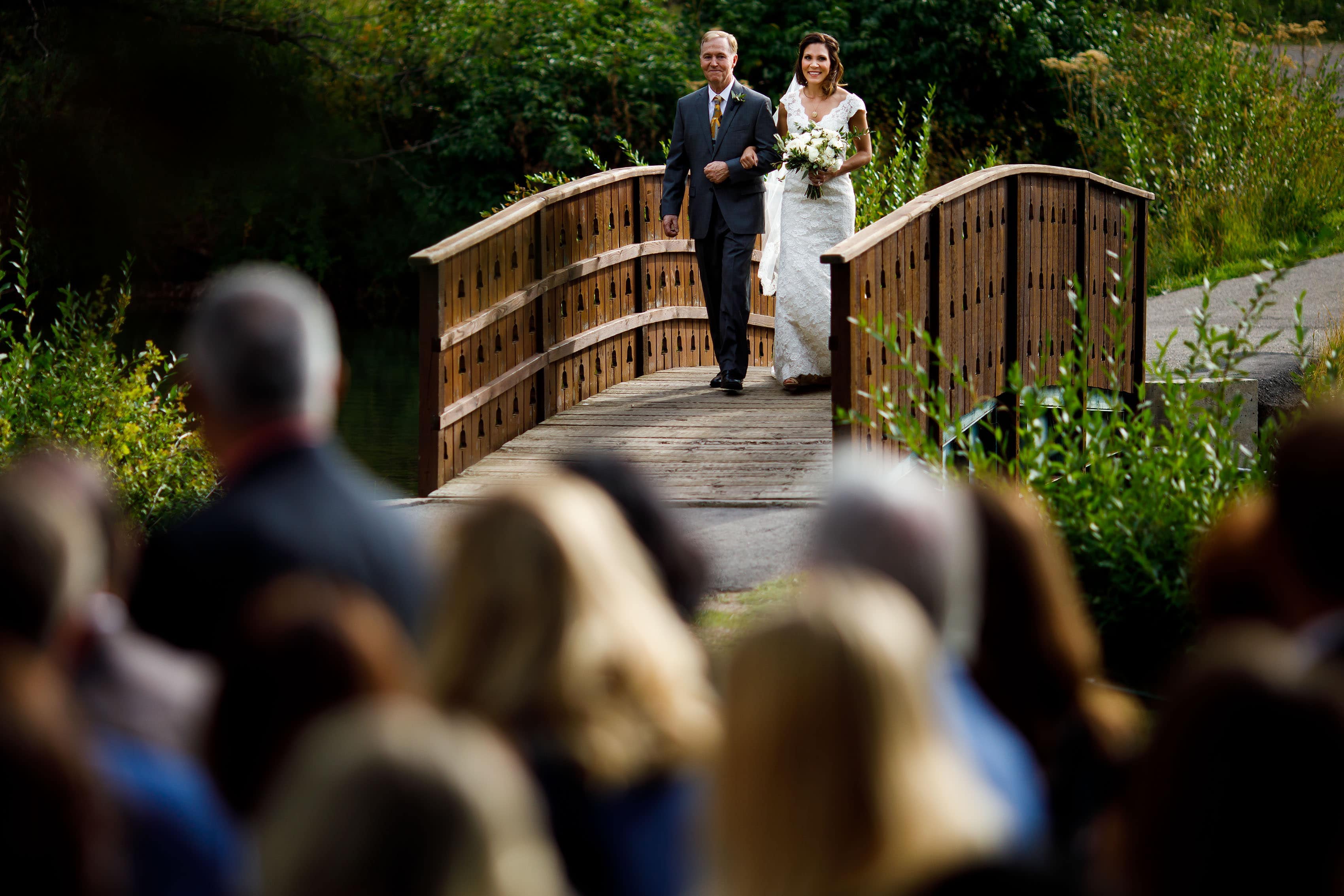 Christine walks with her father across the bride during her Vail Golf Club wedding