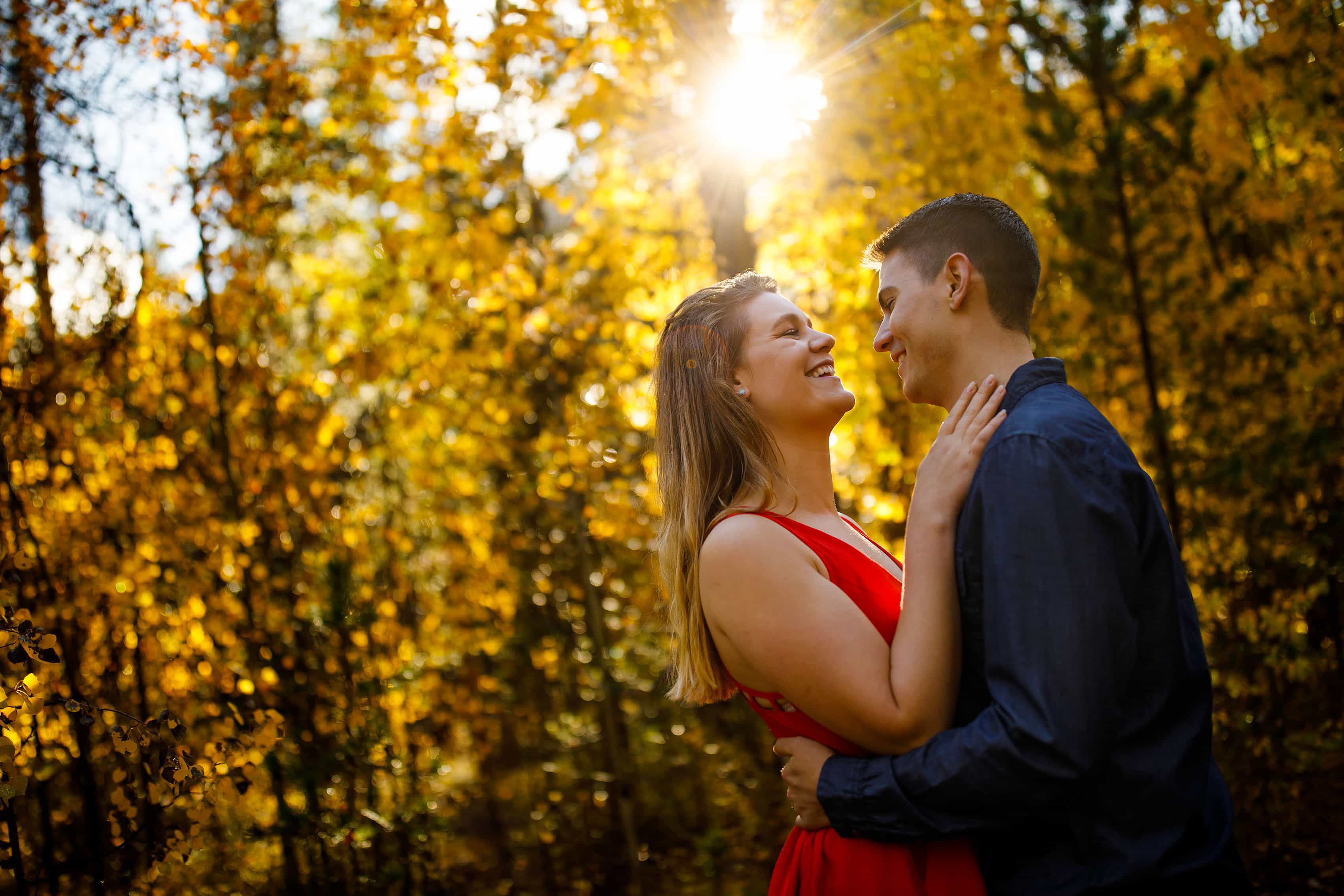 Holly and Hayden share a laugh during their Colorado fall engagement photos in a grove of yellow aspen trees