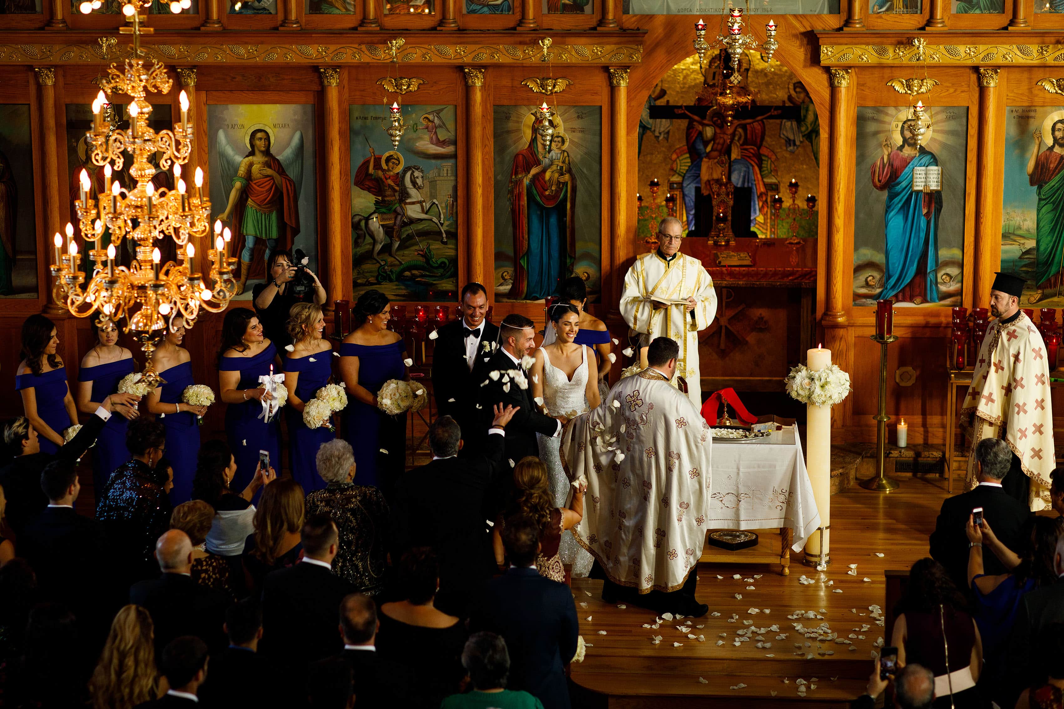 The bride and groom are showered with rose pedals as they participate in the ceremonial walk around the table during their Albuquerque Greek Orthodox wedding at Saint George