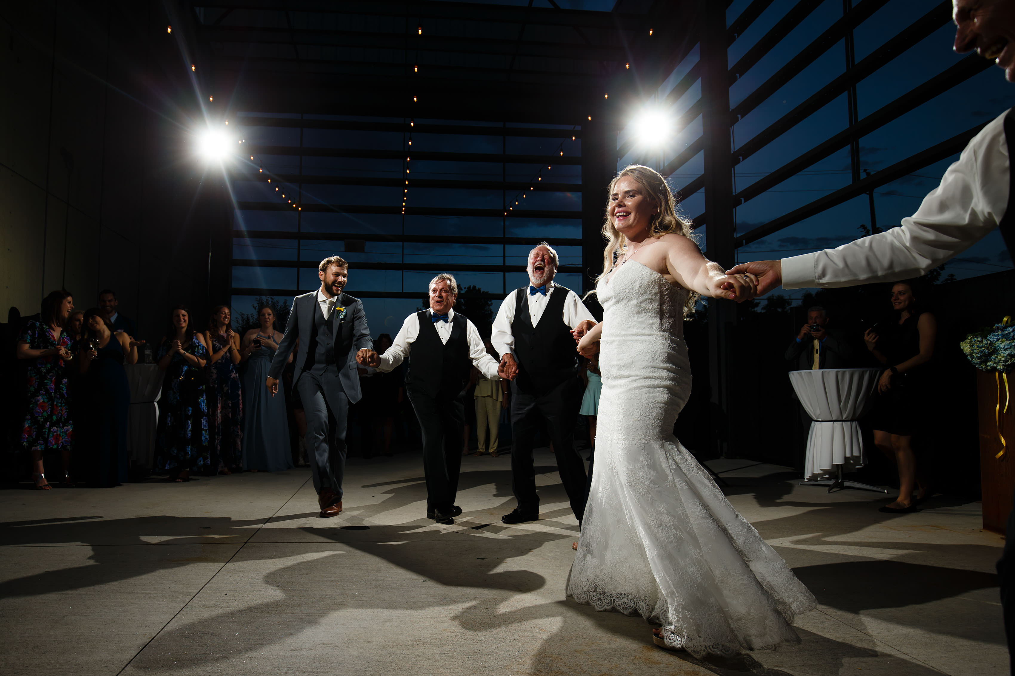 The bride and groom dance with their family during twilight at Space Gallery