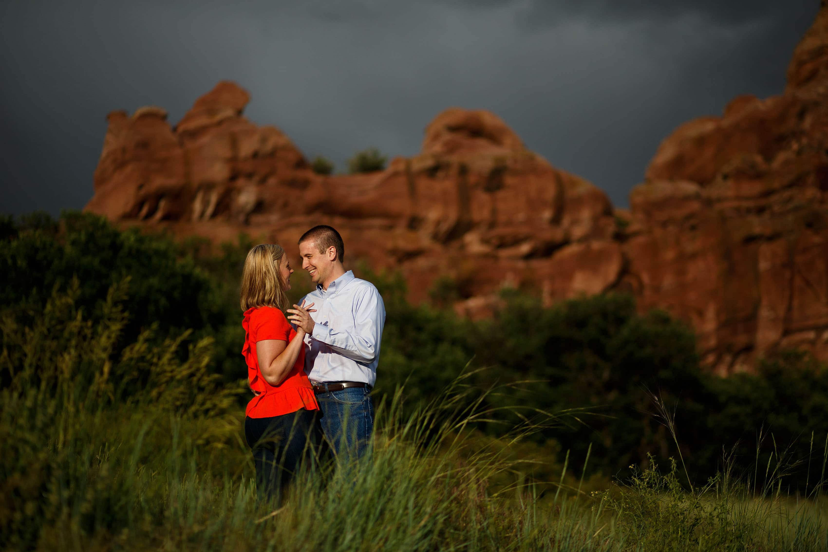 A couple embrace near a rock formation during their Roxborough State Park engagement photos
