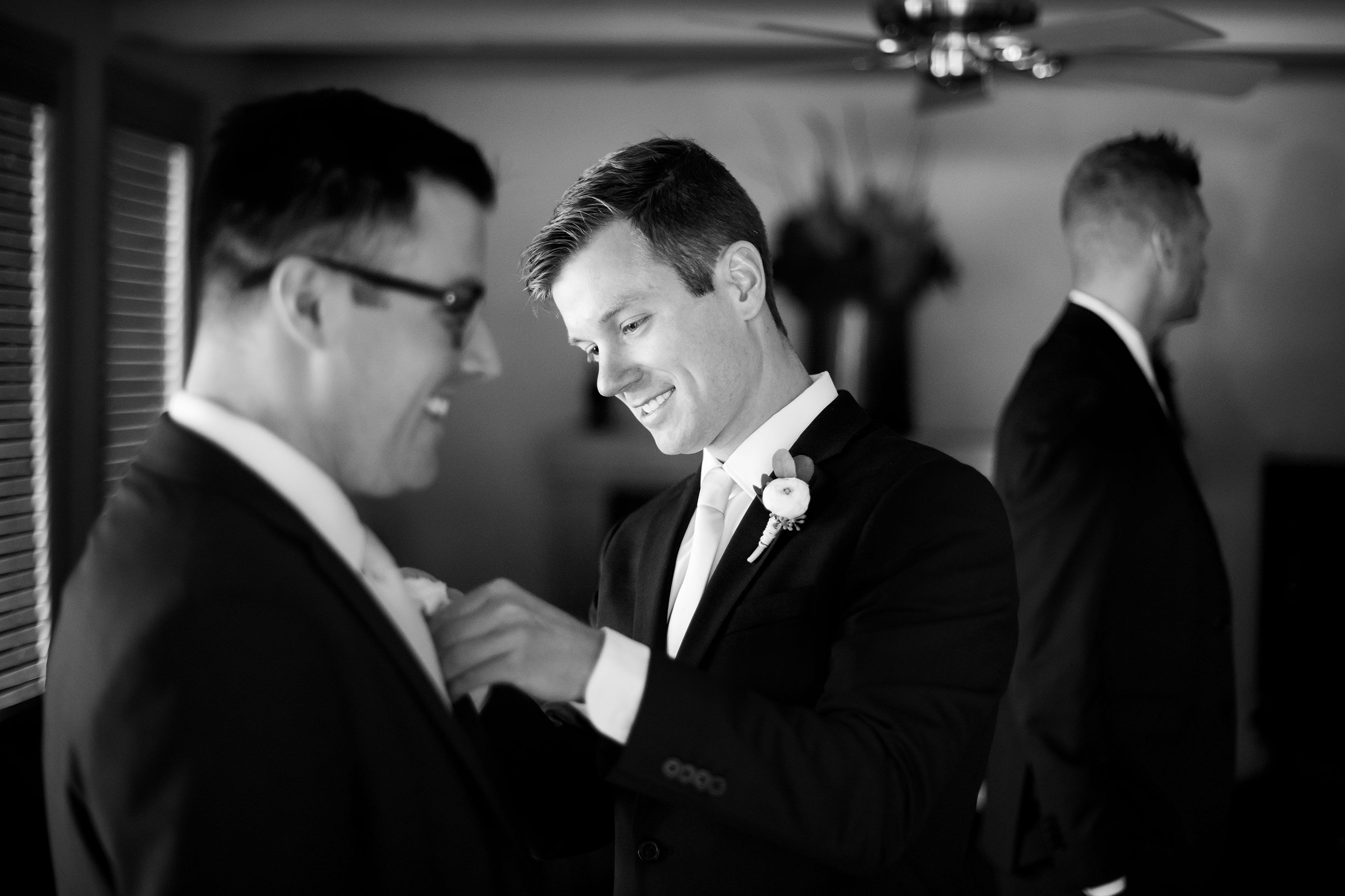 The groom helps groomsmen get ready before the wedding
