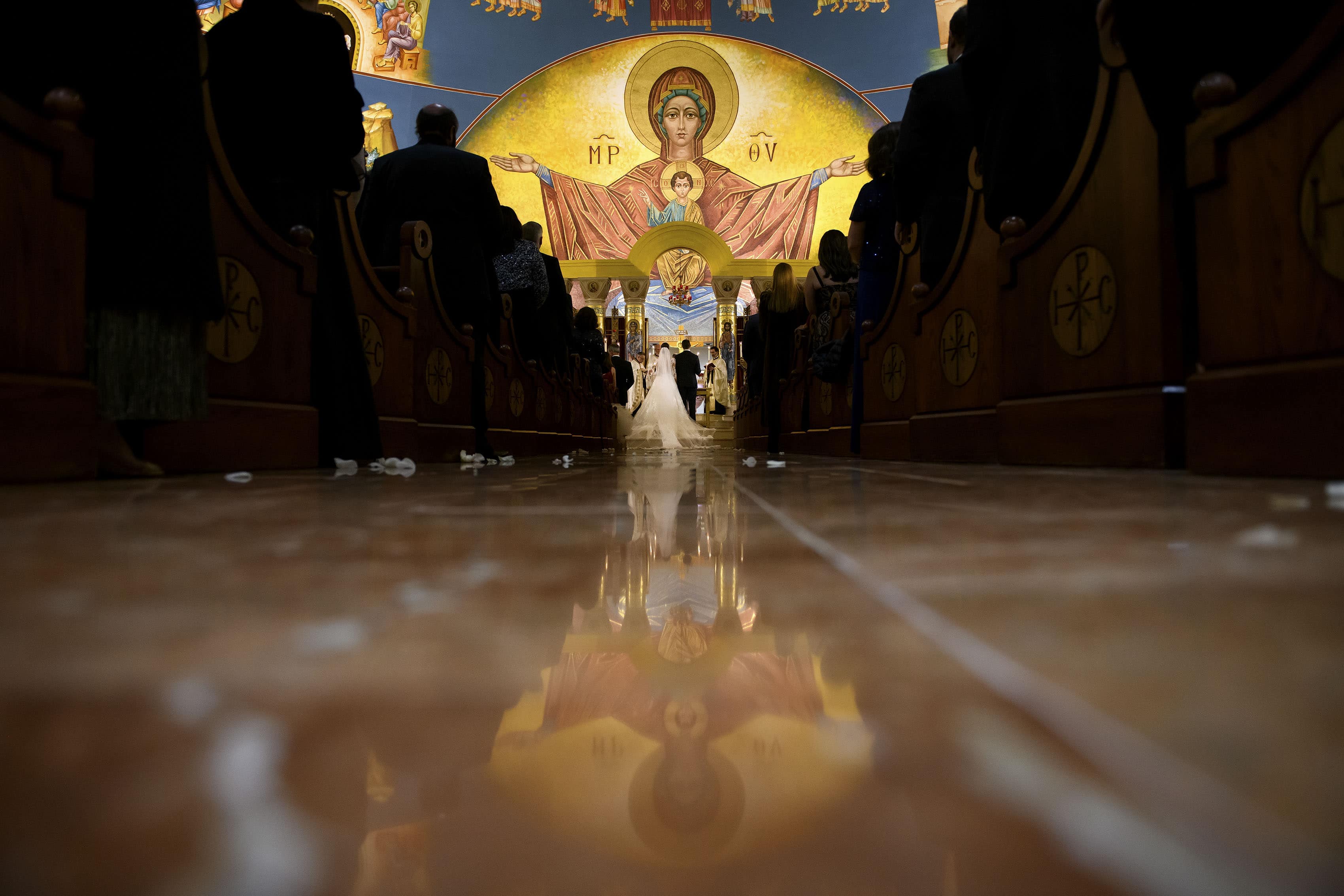 The bride and groom stand at the altar at the Assumption of the Theotokos Greek Orthodox Cathedral during their wedding ceremony
