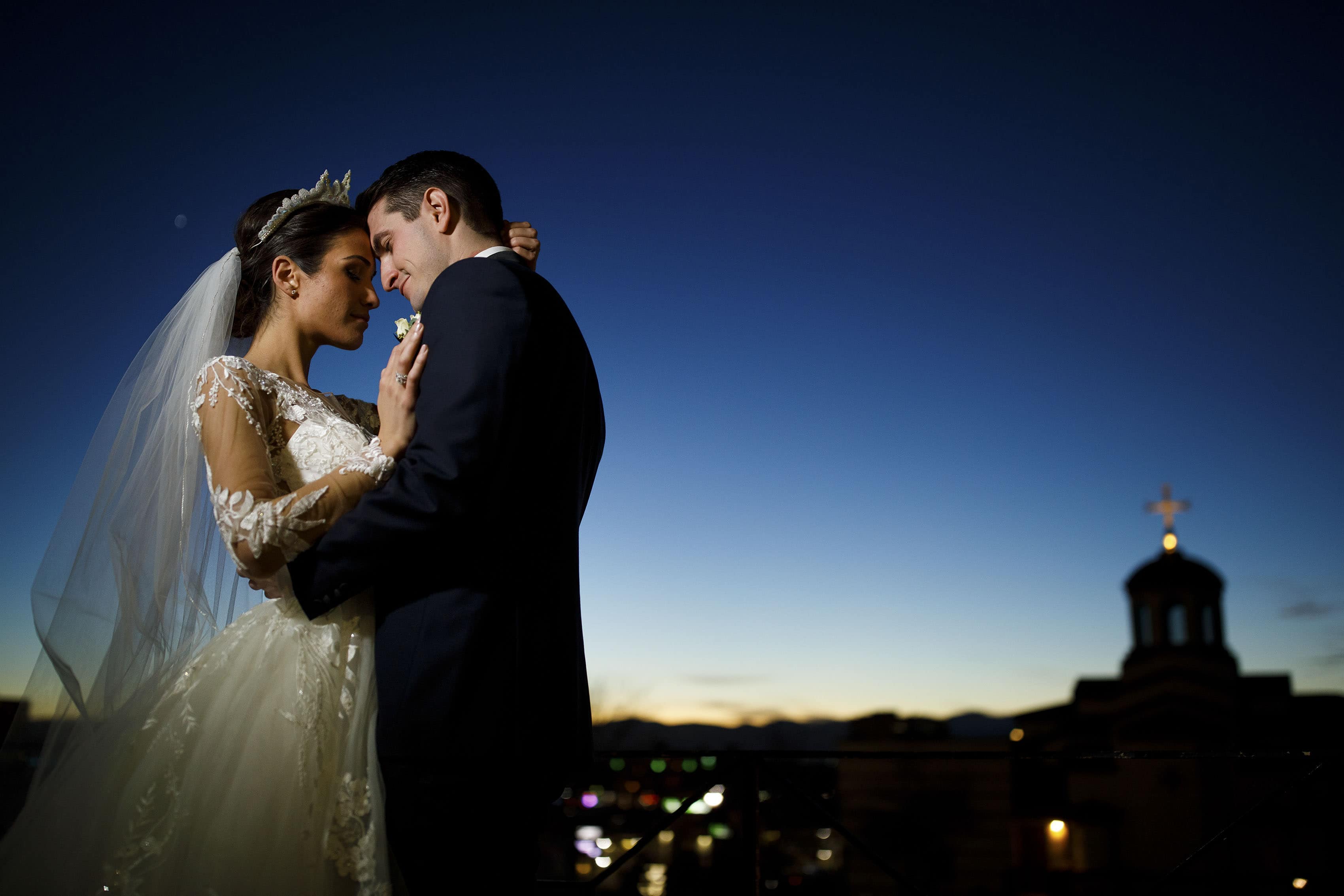 Newlyweds Alex and Ioanna share a moment outside the Assumption of the Theotokos Greek Orthodox Cathedral at twilight