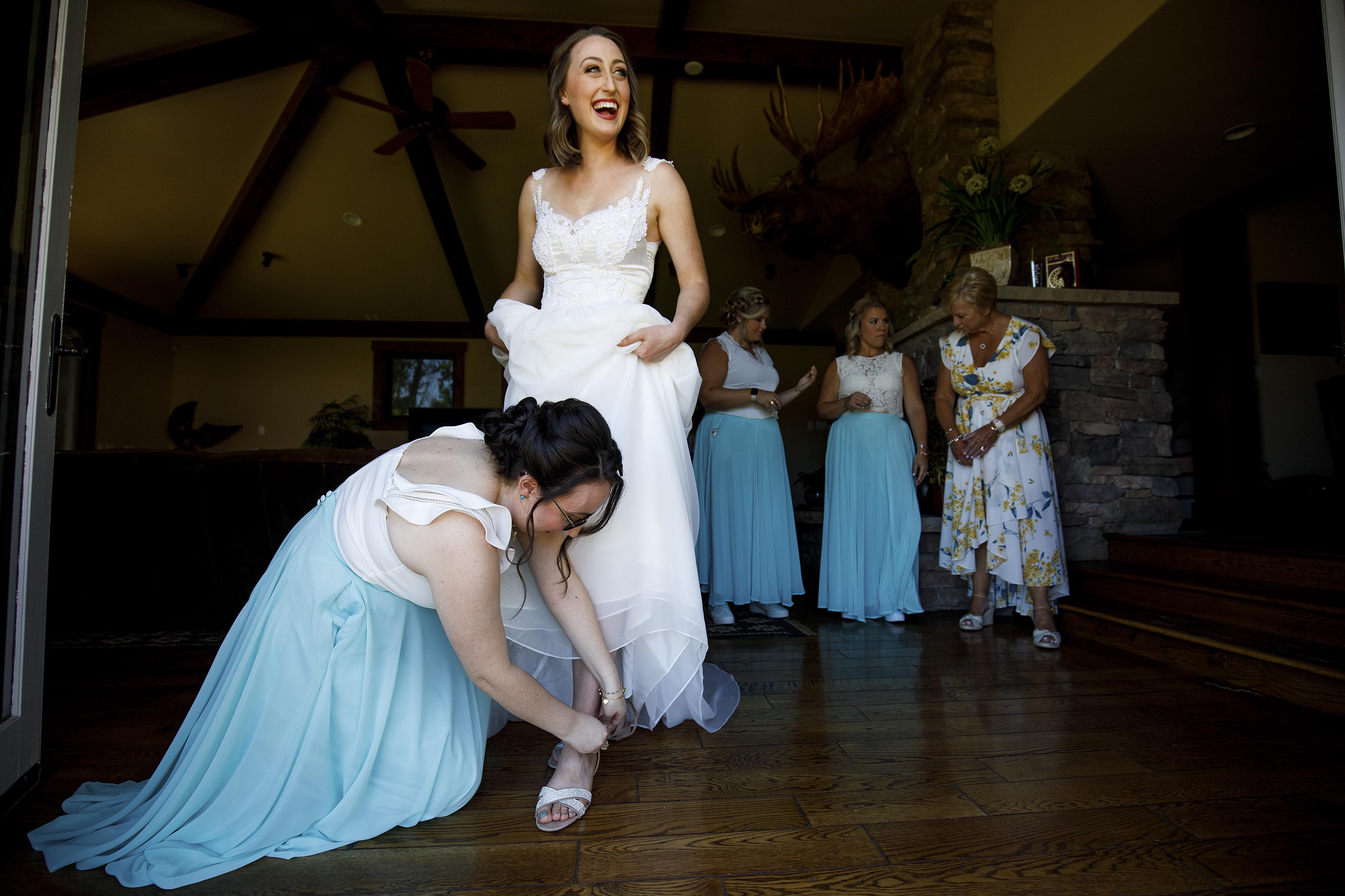 The bride laughs while getting dressed before her wedding at 4 Eagle Ranch in Wolcott, CO