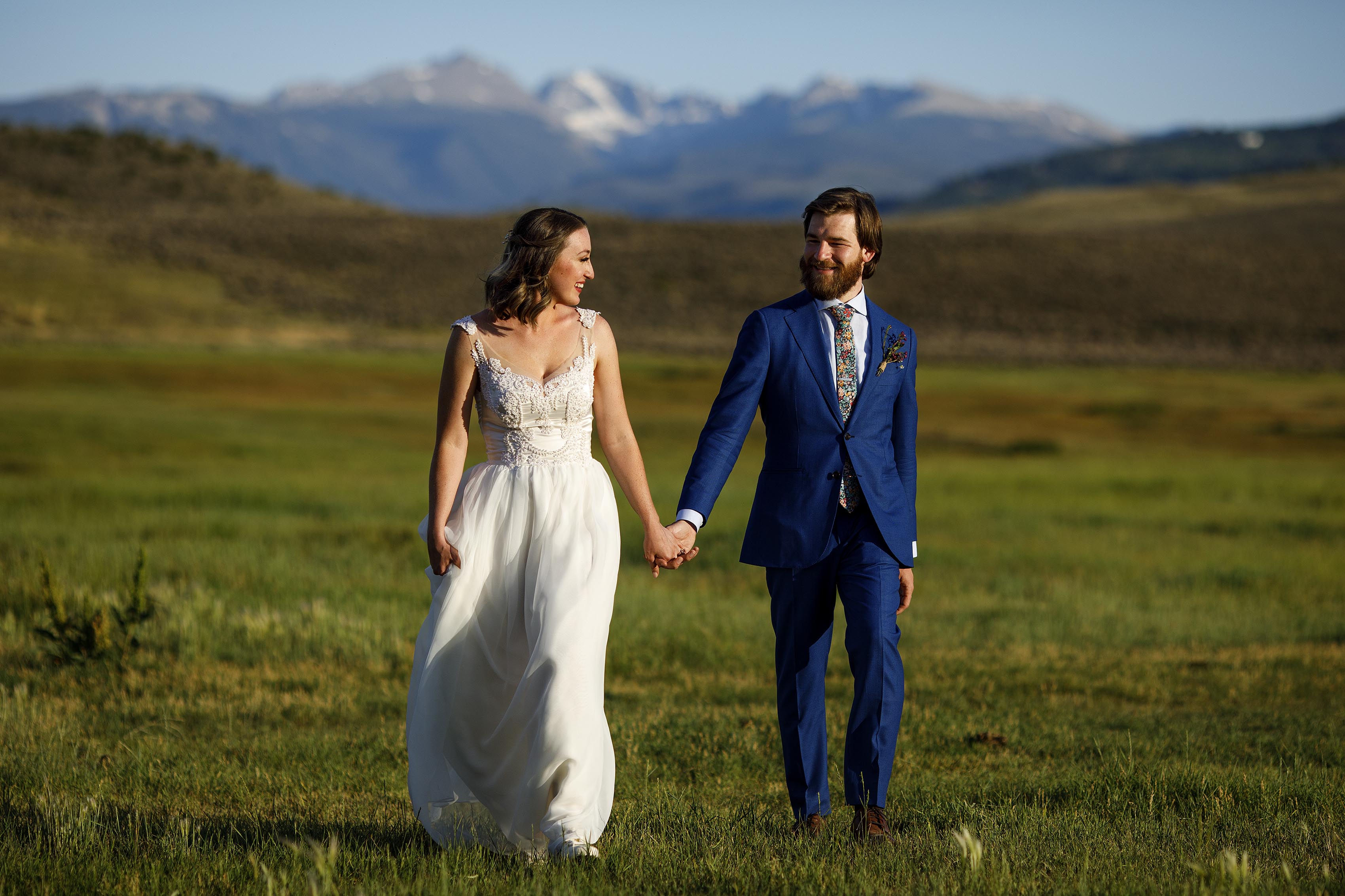 The newlyweds walk through a field in Wolcott, CO at 4 Eagle Ranch during their wedding day