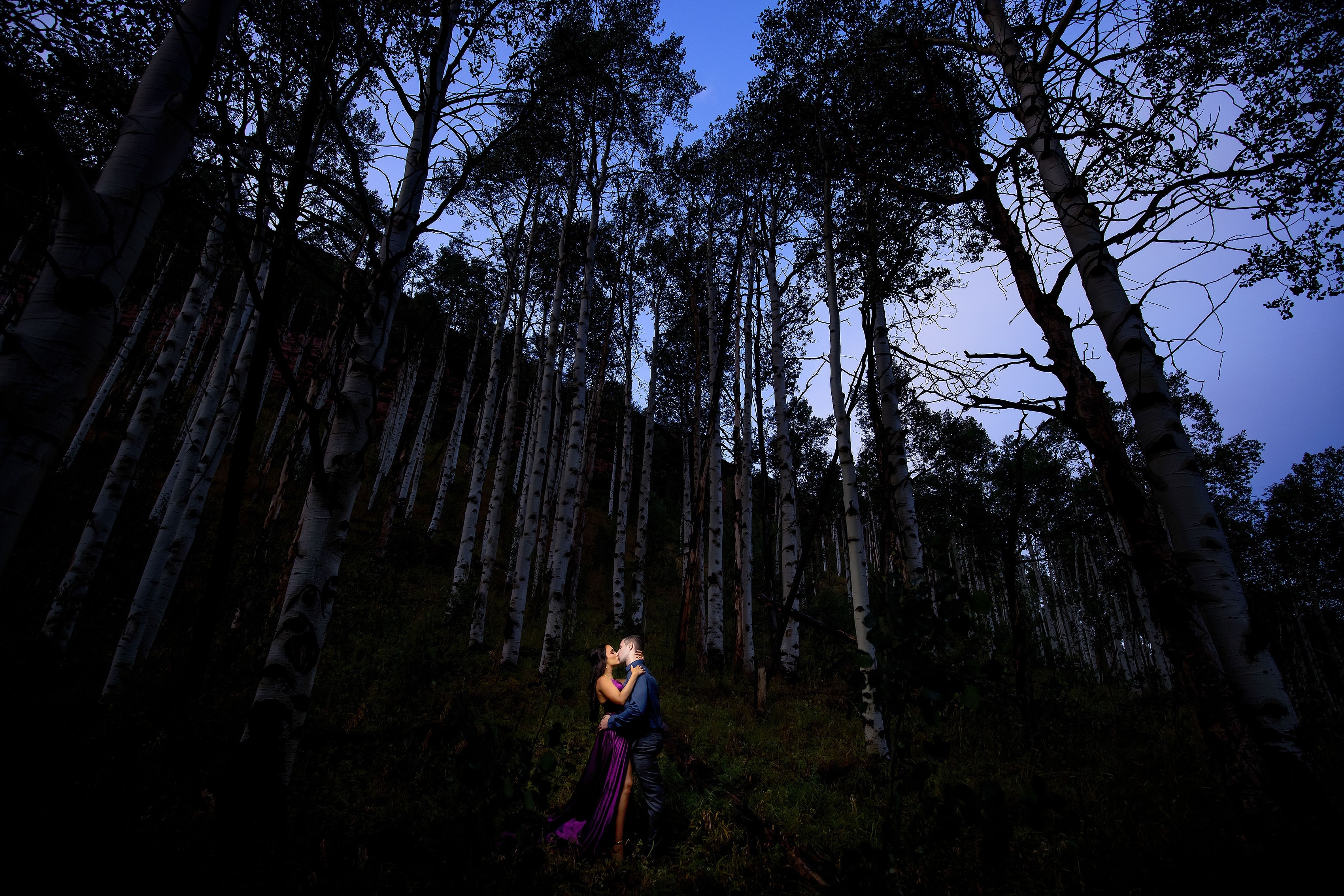 A couple share a kiss in the aspen trees near Vail, Colorado during their engagement