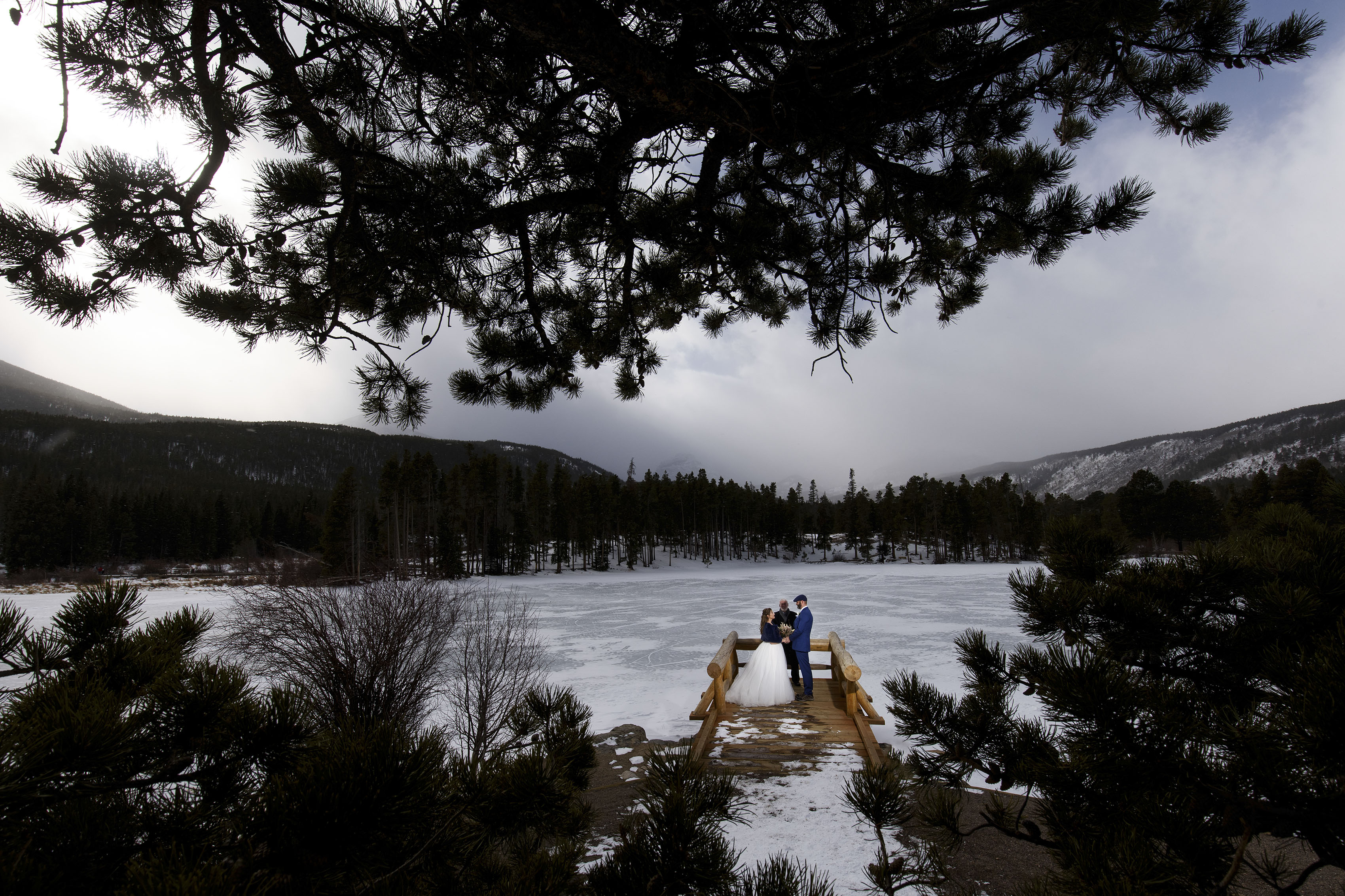 A couple stands on the bridge at Sprague Lake in Rocky Mountain National Park during their winter elopement